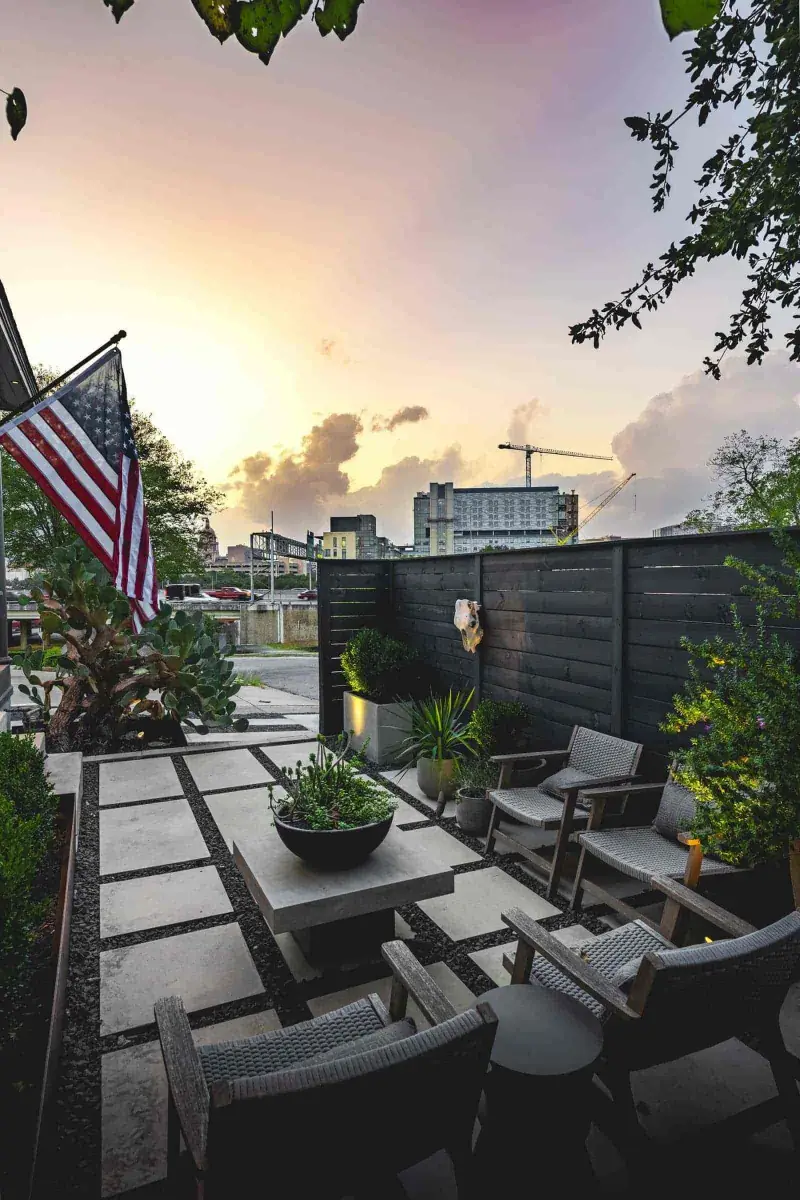Urban patio with large concrete pavers and black privacy fence