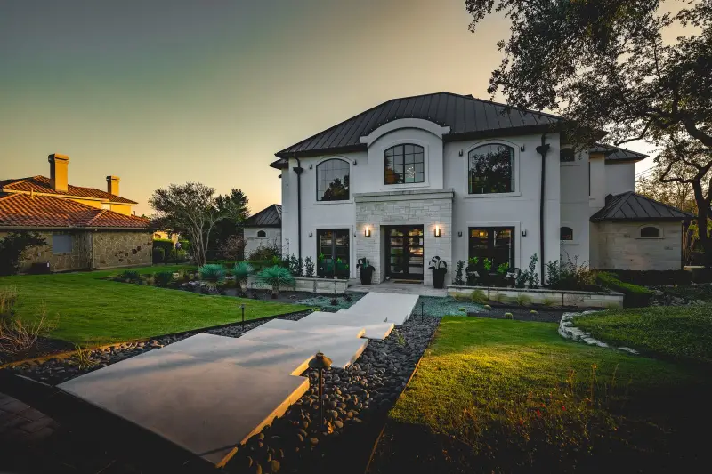 Large white home with wide steps and lawn at dusk